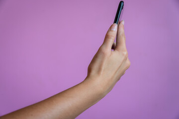 female hand holding mobile phone against a pink , Mauve background. Room for text