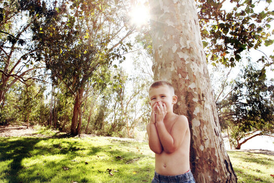 Boy in Park Giggling Covering His Mouth