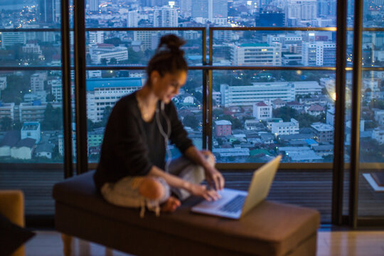 Woman working from her laptop - focus on the city behind her