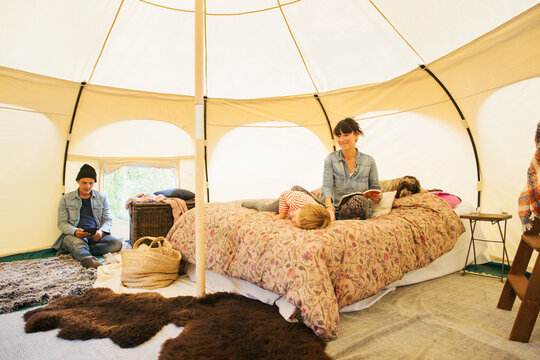Glamping - Caucasian Family of Three Relaxing on Bed Inside Large Circular Yurt