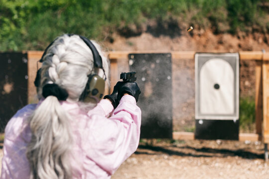 Shooting: Mature Woman Firing Handgun At Target With Cartridge Expelled