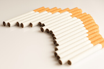 Cigarettes with a yellow filter lie on a white surface