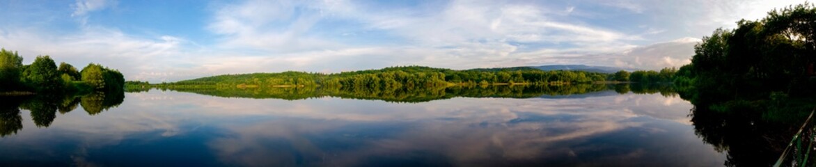 Obraz na płótnie Canvas Panoramic view of a calm lake on a sunny summer day