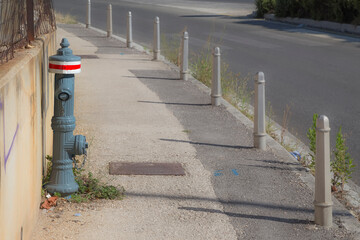 fire hydrant with a bright red stripe against a concrete wall