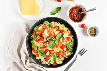 Tomato and bacon pasta with parmesan cheese and basil leaves