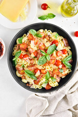 Tomato and bacon pasta with parmesan cheese and basil leaves