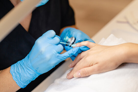 Close-up Of Beautician Painting Her Client's Nails In Blue And Yellow Nail Varnish.