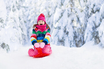 Girl on sled ride. Child sledding. Kid on sledge