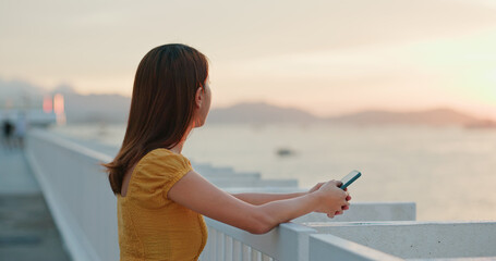Woman hold with cellphone and look at the sunset