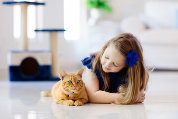 Child playing with cat at home. Kids and pets.