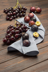 Plum fruits on gray napkin. Half plum with pit. Bunch of grapes.