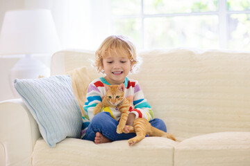 Child playing with cat. Kid and kitten.