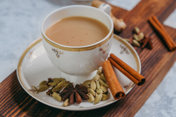 Masala tea. Flavoured tea chai. Traditional Indian hot drink with various spices on a wooden board in a porcelain mug.