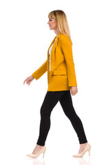 Young Woman In Yellow Jacket And High Heels Is Walking. Side View.