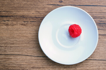 raspberry berry in a white plate on a wooden table