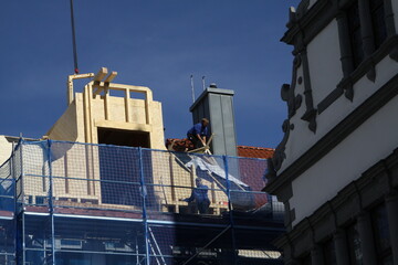 Craftsman, carpenter, roofer at work, preparing for the completion of a roof for a tall building