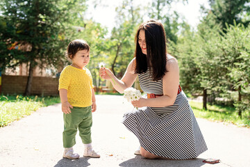 Mother walking her daughter in the park giving her flowers