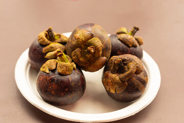 vietnam mangosteen fruit whole round, dark purple lies on a white plate