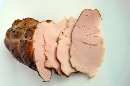 A piece of sliced smoked home made turkey breast isolated on white
