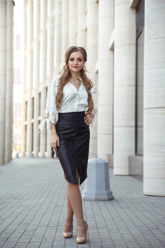Attractive adult woman in elegant business attire in full length outside.