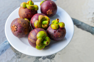 set of fruity round lilac mangosteen lies on a white plate close-up