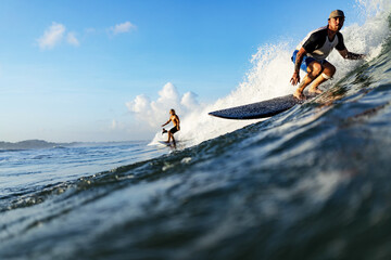 Three young adult surfers rides the wave of the ocean at the surf spot. High quality photo