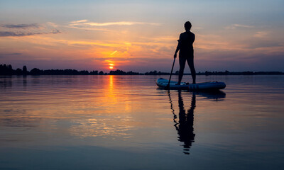 Silhouette of a person on a SUP board sunset