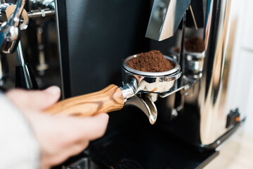 Frisch gemahlener Kaffee fällt in Siebträger vom Kaffee Vollautomat für die Zubereitung eines...