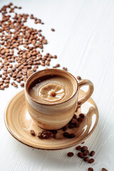 Latte and coffee beans on a white wooden table.