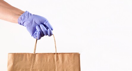 Home delivery food. Grocery store shopping delivery one person giving paper bag wearing blue glove as protection for COVID-19 Coronavirus precautions. Shopping bag with Merchandise, goods, food. 