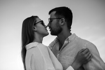Black and white  portrait of a couple embracing against the background of the sky. Happy young couple in love wearing shirts. They spending time together at the seaside, hugging.