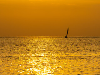 ヨットと夕暮れの金色に輝く海
