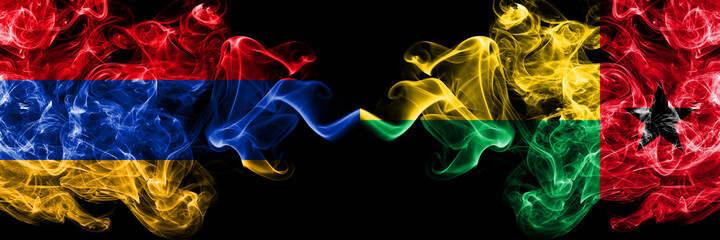 Armenia vs Guinea Bissau smoky mystic flags placed side by side. Thick colored silky abstract smoke flags