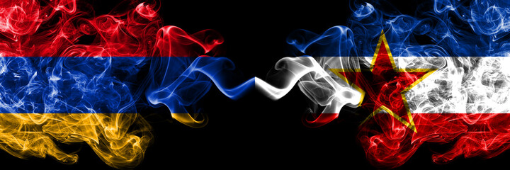 Armenia vs Yugoslavia smoky mystic flags placed side by side. Thick colored silky abstract smoke flags