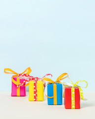 Four colorful gift boxes on a pastel background. Copy space. Front view.