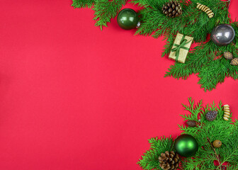 Weihnachtsdekoration auf rotem Hintergrund mit Tannengrün, Geschenk und Weihnachtskugel