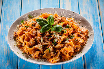Tagliatelle with marinara sauce, meat and parmesan on wooden table
