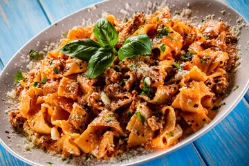 Tagliatelle with marinara sauce, meat and parmesan on wooden table
