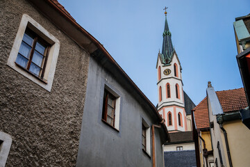 Fototapeta na wymiar Medieval narrow street with colorful renaissance historical buildings, tower of the St. Vitus Church in the center of Cesky Krumlov, South Bohemia, Czech Republic
