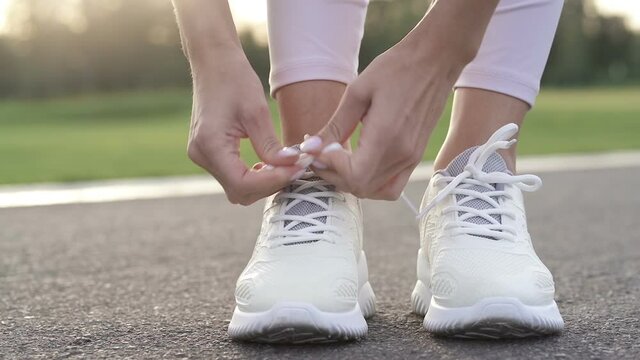 Close-up. Woman tie shoelaces on the sneakers. Slowmotion.