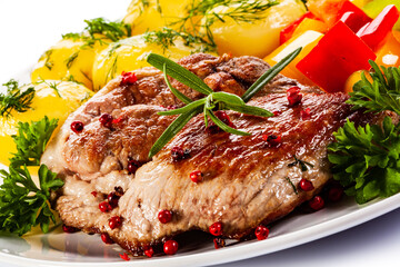 Grilled steak with boiled potatoes and vegetables on white background

