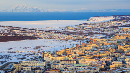Fototapeta premium Top view of the city of Magadan. Beautiful aerial cityscape with residential and administrative buildings and a large cathedral. Sea bay and mountains in the distance. Magadan Region, Far East Russia.