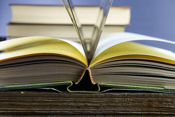 Close up of isolated open book hinge with flying pages, stack of blurred books background