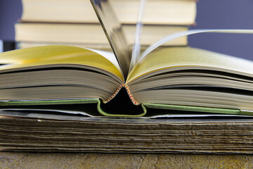 Close up of isolated open book hinge with flying pages, stack of blurred books background