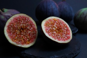 Macro closeup of two isolated fresh ripe sliced halves fig fruits wioth black slate stone background