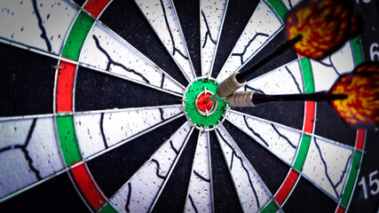 Dart board with arrow hitting the bullseye close up. Hitting the target