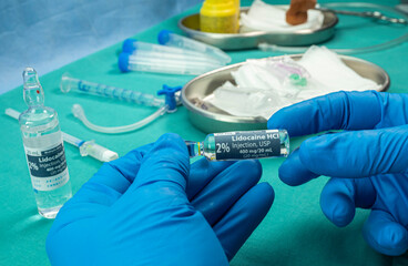 Nurse holds ampoule of anesthesia, preparation to extract cerebrospinal fluid in a person affected...
