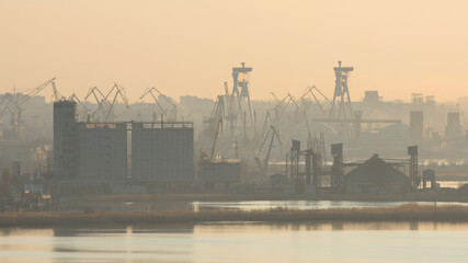 Silhouette of an industrial city. Port and harbor cranes. Panoramic photo.