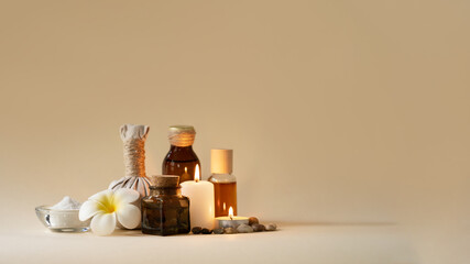Beautiful spa composition with candles, frangipani flower, oil flasks, bowl with salt and herbal ball. Copy space.