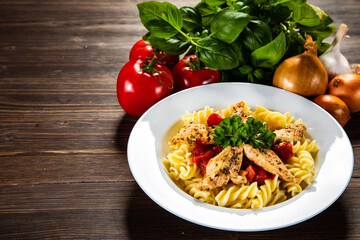 Chicken ragout with fusilli on wooden table
